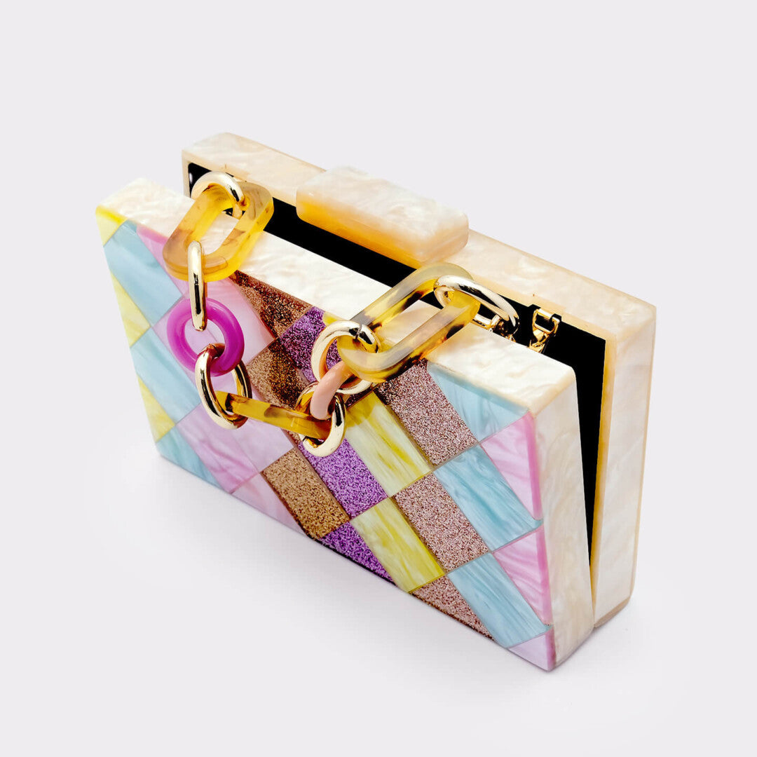L’APOGÉE Eden rectangular acrylic clutch featuring geometric pastel panels in pink, yellow, aqua blue, lilac, and glitter textures designed for playful statement styling, parties, and colorful fashion moments.