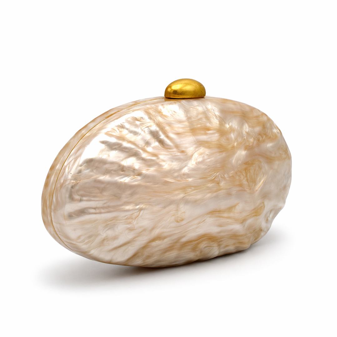 L’APOGÉE Lithéa oval acrylic clutch featuring glossy beige marbled finishes, a smooth sculptural silhouette, and elegant metallic clasp detailing designed for refined evening styling and luxury fashion moments.