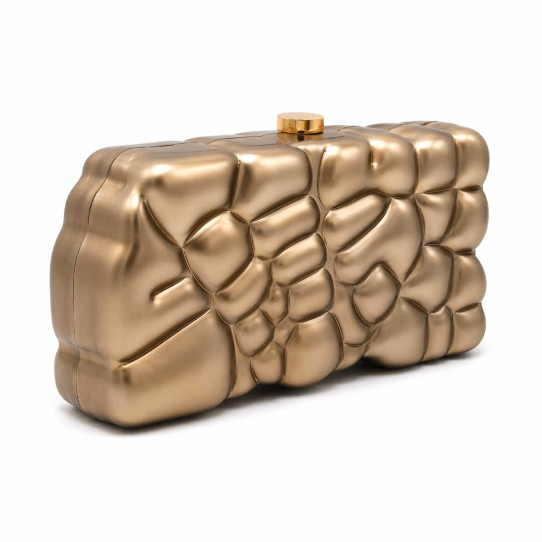 L’APOGÉE Gravée in Brown textured acrylic clutch featuring warm caramel brown marbled finishes, an embossed sculptural surface, and a structured rectangular silhouette designed for sophisticated evening styling and statement fashion looks.