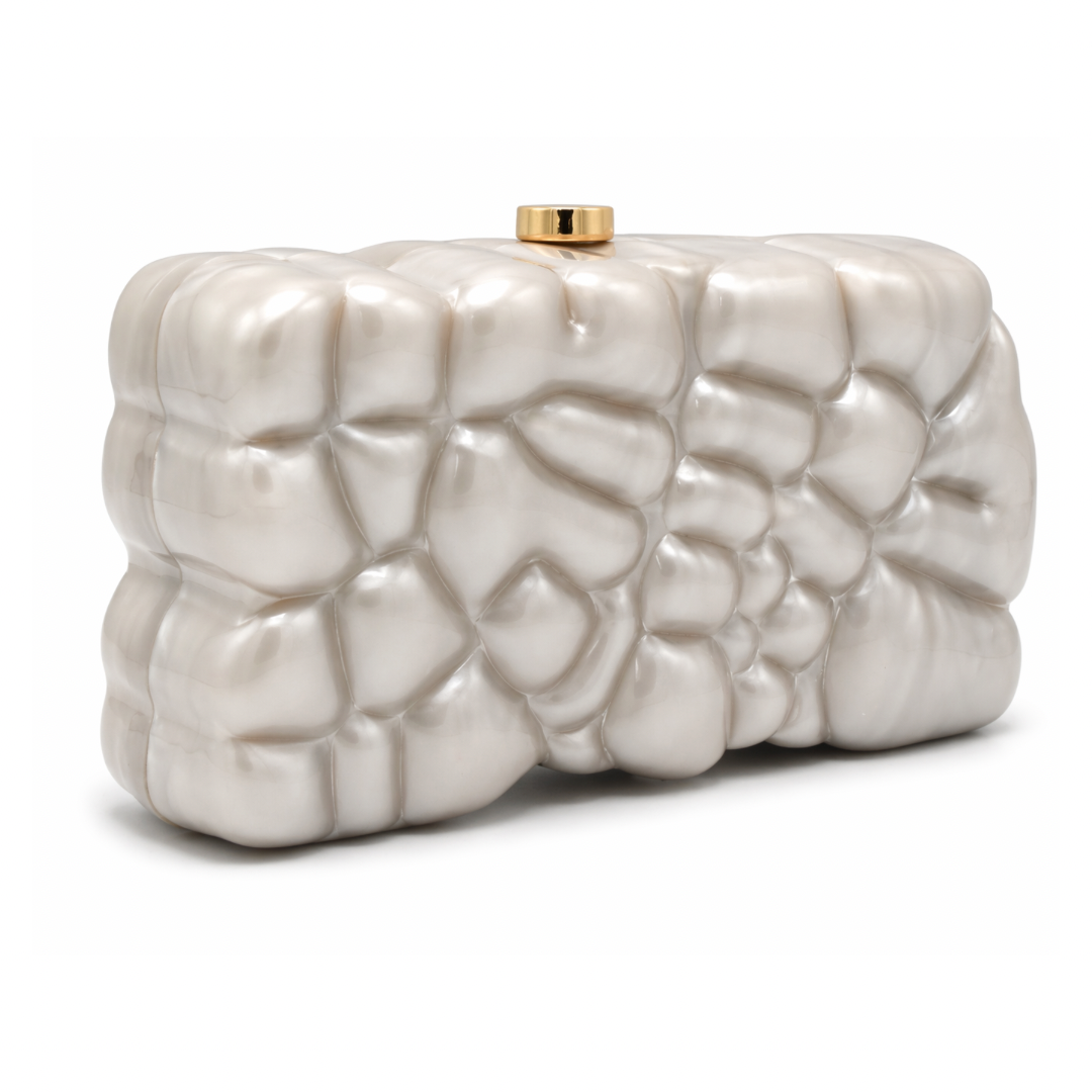 L’APOGÉE Gravée in Pearl textured acrylic clutch featuring pearly ivory finishes, an embossed sculptural surface, and a structured rectangular silhouette designed for bridal styling, elegant evenings, and artistic luxury fashion looks.