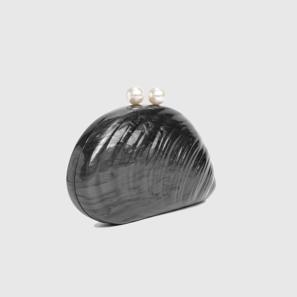 L’APOGÉE Elefteria black shell-shaped evening bag featuring a sculptural glossy design for weddings, formal events, luxury dinners, and elegant statement occasion styling.