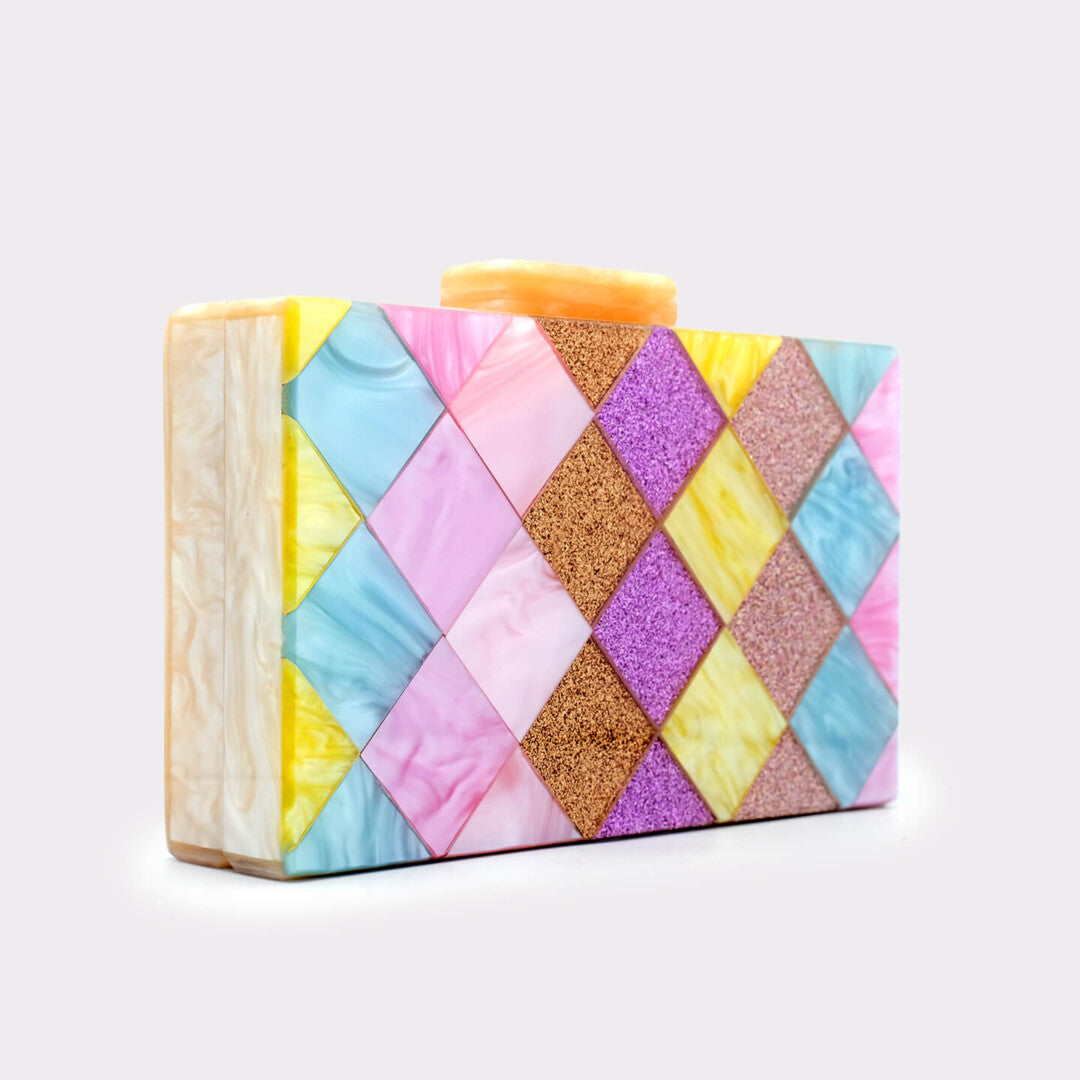 L’APOGÉE Eden rectangular acrylic clutch featuring geometric pastel panels in pink, yellow, aqua blue, lilac, and glitter textures designed for playful statement styling, parties, and colorful fashion moments.