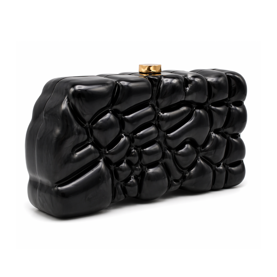L’APOGÉE Gravée in Black textured acrylic clutch featuring glossy black finishes, an embossed sculptural surface, and a structured rectangular silhouette designed for modern evening styling and bold monochrome fashion statements.