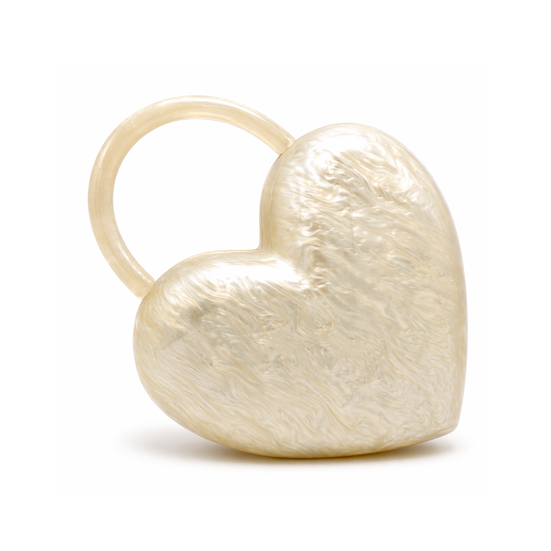 L’APOGÉE Amouré sculptural heart-shaped acrylic clutch featuring pearly ivory textures and an integrated circular handle designed for romantic evening styling, bridal looks, and statement fashion moments.