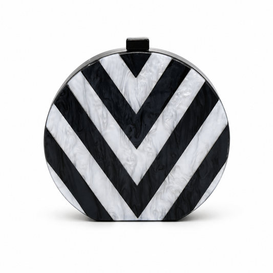 L’APOGÉE Chroma round acrylic clutch featuring bold black and white geometric striped patterns with a sculptural circular silhouette designed for modern evening styling and monochrome fashion statements.
