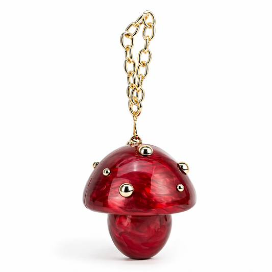 L’APOGÉE Fungo in Red sculptural mushroom acrylic clutch featuring glossy red marbled textures, gold stud detailing, and a gold chain handle designed for playful statement styling, fashion events, and artistic evening looks.