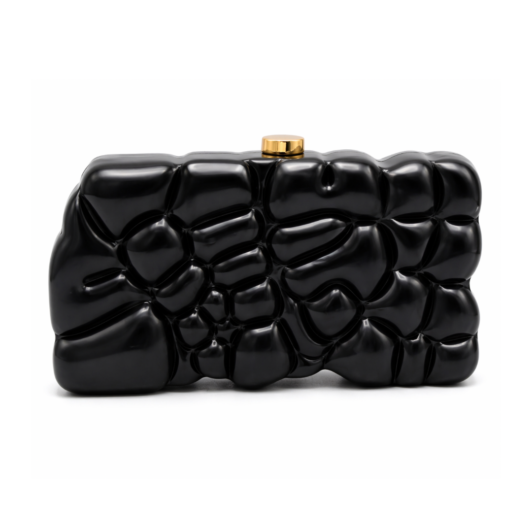L’APOGÉE Gravée in Black textured acrylic clutch featuring glossy black finishes, an embossed sculptural surface, and a structured rectangular silhouette designed for modern evening styling and bold monochrome fashion statements.