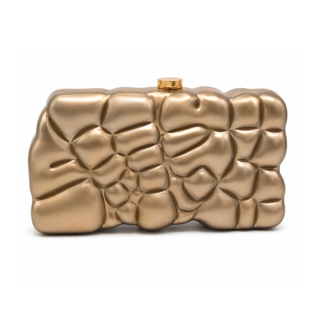 L’APOGÉE Gravée in Brown textured acrylic clutch featuring warm caramel brown marbled finishes, an embossed sculptural surface, and a structured rectangular silhouette designed for sophisticated evening styling and statement fashion looks.