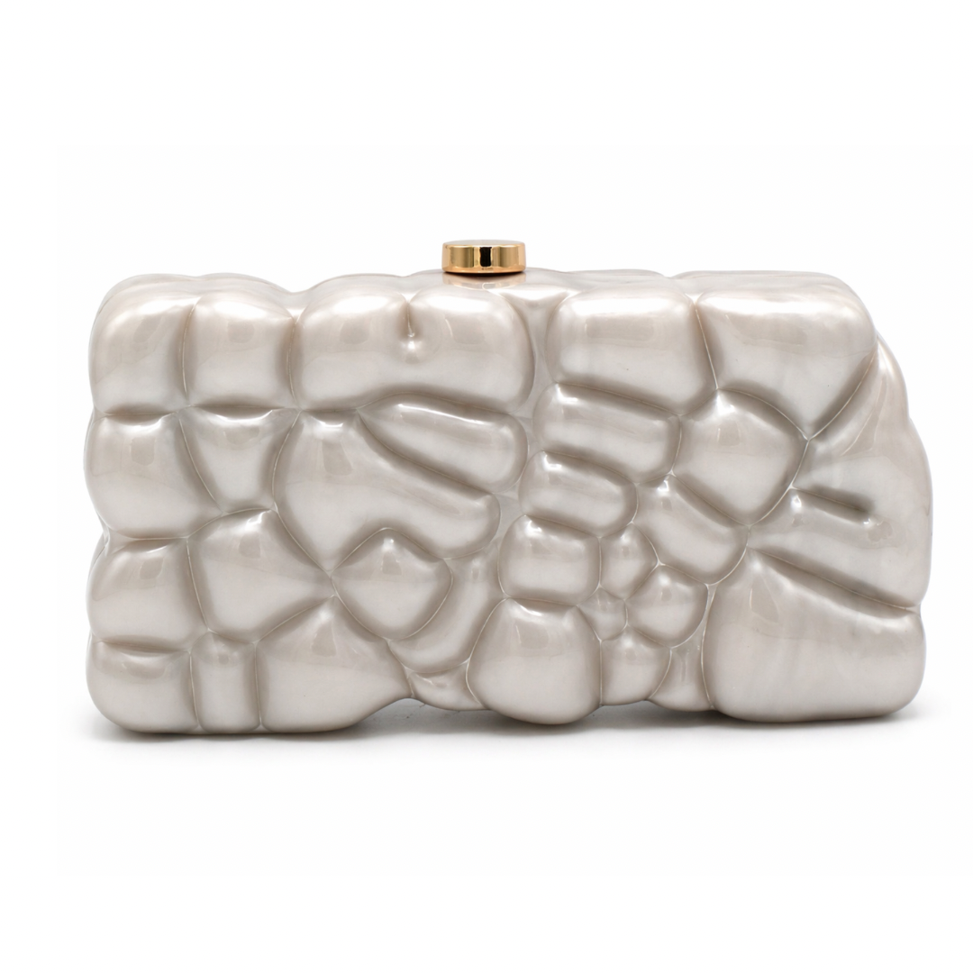 L’APOGÉE Gravée in Pearl textured acrylic clutch featuring pearly ivory finishes, an embossed sculptural surface, and a structured rectangular silhouette designed for bridal styling, elegant evenings, and artistic luxury fashion looks.