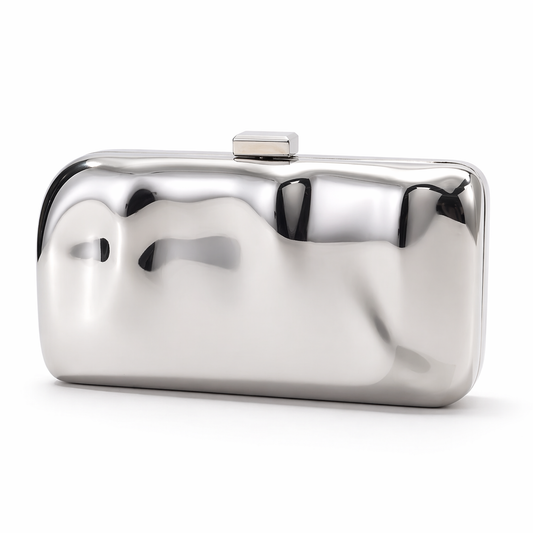 L’APOGÉE Métaléa metallic clutch featuring reflective silver finishes, an artistic sculptural silhouette, and modern futuristic detailing designed for glamorous evening styling and luxury fashion looks.