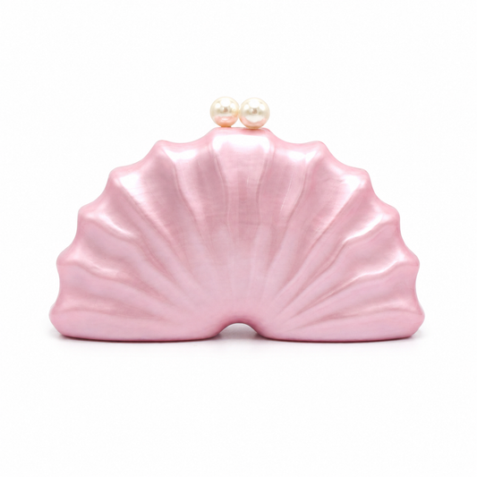 L’APOGÉE Naïelle shell-inspired acrylic clutch featuring soft blush pink finishes, sculptural oceanic curves, and pearl clasp detailing designed for feminine evening styling and elegant statement fashion looks.