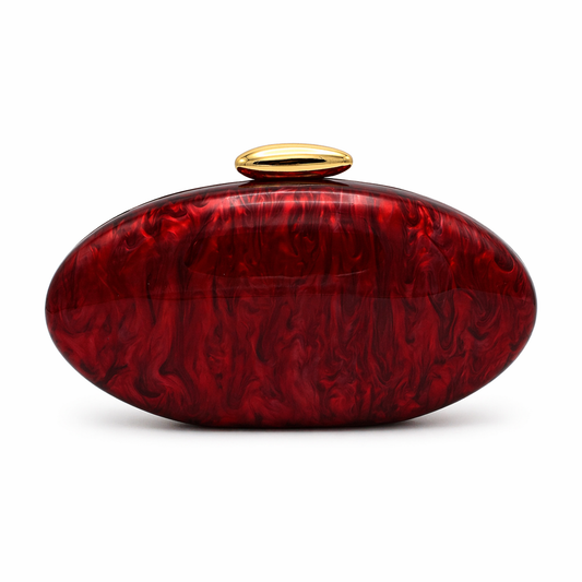 L’APOGÉE Rouge Éclat oval acrylic clutch featuring deep ruby red marbled finishes, a glossy sculptural silhouette, and elegant metallic clasp detailing designed for glamorous evening styling and bold luxury fashion moments.