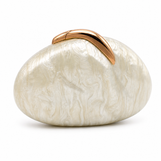 L’APOGÉE Sovana in Ivory acrylic clutch featuring a pearly ivory marbled finish, smooth pebble-inspired silhouette, and sculptural gold metallic handle designed for minimalist luxury evening styling.