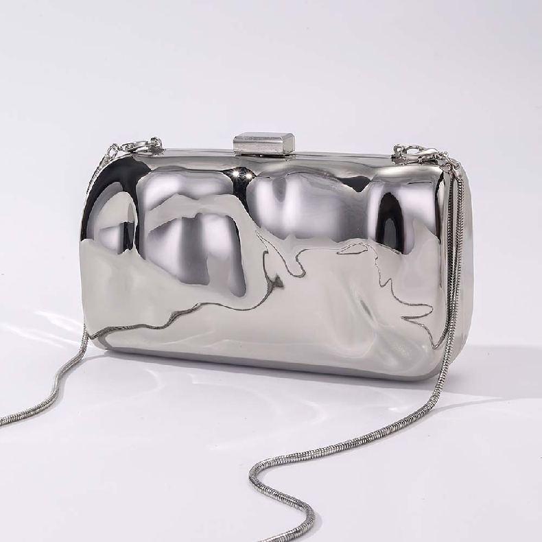 L’APOGÉE Métaléa metallic clutch featuring reflective silver finishes, an artistic sculptural silhouette, and modern futuristic detailing designed for glamorous evening styling and luxury fashion looks.